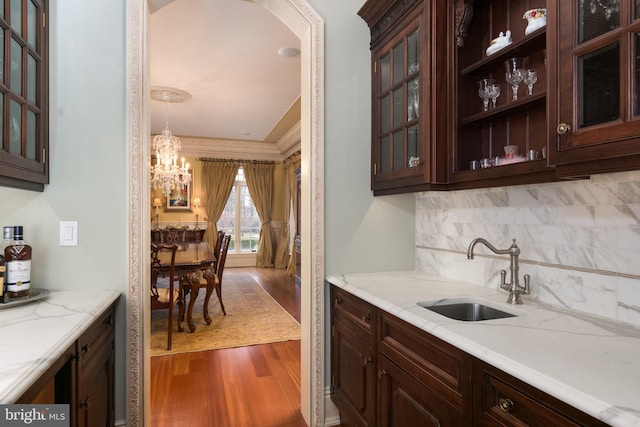 kitchen with decorative light fixtures, decorative backsplash, wood-type flooring, sink, and a chandelier