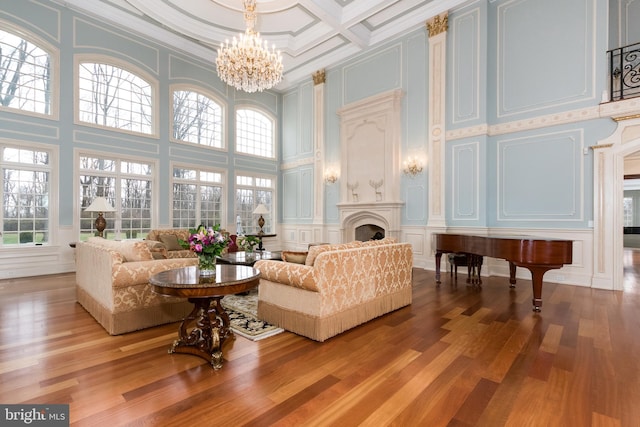 living room with crown molding, an inviting chandelier, a towering ceiling, and light wood-type flooring