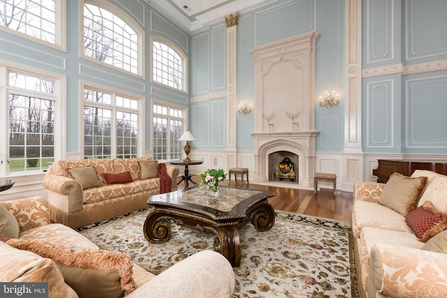 living room with hardwood / wood-style floors, crown molding, and a towering ceiling