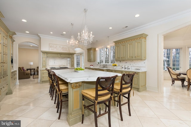 kitchen featuring crown molding, pendant lighting, light stone counters, and a center island