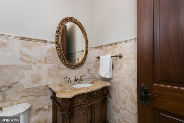 bathroom with tile walls, toilet, and vanity