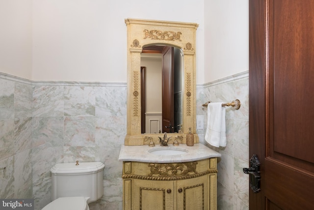 bathroom with tile walls, toilet, and vanity