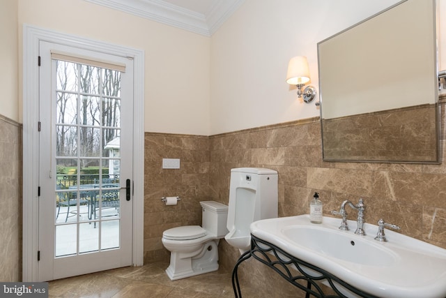 bathroom with toilet, tile walls, sink, and crown molding