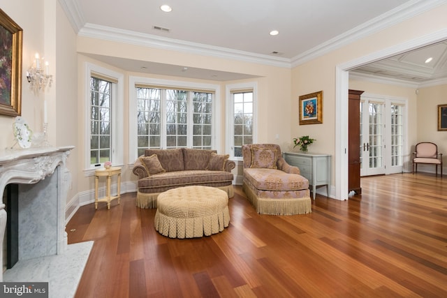 living area featuring wood-type flooring, a fireplace, french doors, and crown molding