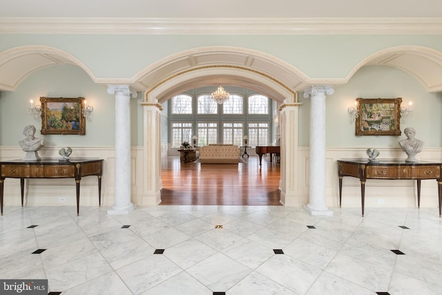 hallway featuring an inviting chandelier, ornamental molding, and decorative columns