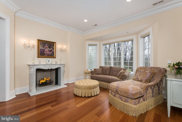 living room featuring hardwood / wood-style flooring, ornamental molding, and a premium fireplace