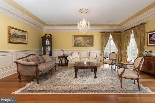 sitting room featuring wood-type flooring, crown molding, and an inviting chandelier