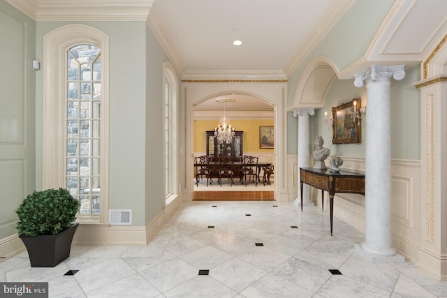 corridor with an inviting chandelier, ornamental molding, and decorative columns