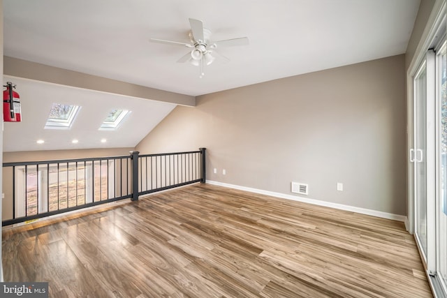 additional living space featuring ceiling fan, vaulted ceiling with skylight, plenty of natural light, and light hardwood / wood-style floors