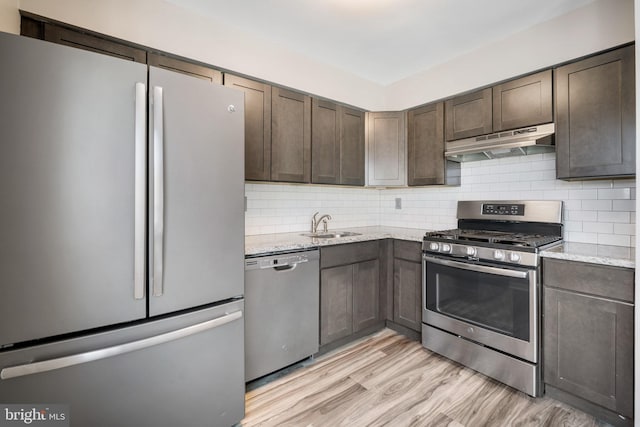 kitchen featuring stainless steel appliances, sink, light hardwood / wood-style floors, and light stone countertops