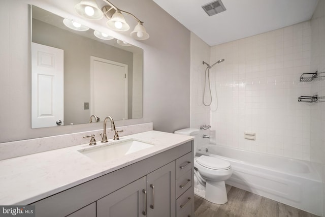 full bathroom featuring toilet, tiled shower / bath combo, wood-type flooring, and vanity