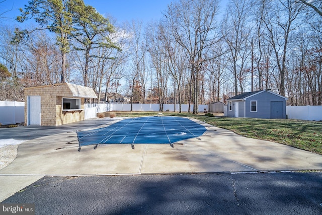 view of pool featuring a garage, an outbuilding, and a patio