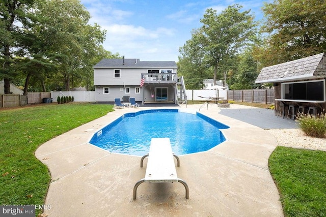 view of swimming pool with a diving board, a patio area, a yard, and an outdoor bar