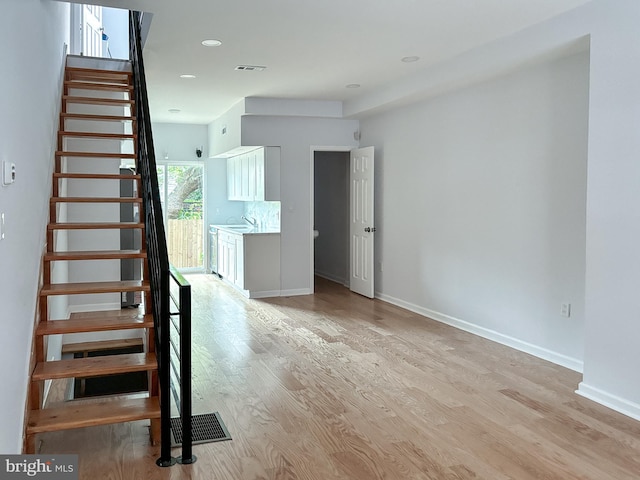 stairs featuring hardwood / wood-style flooring and sink