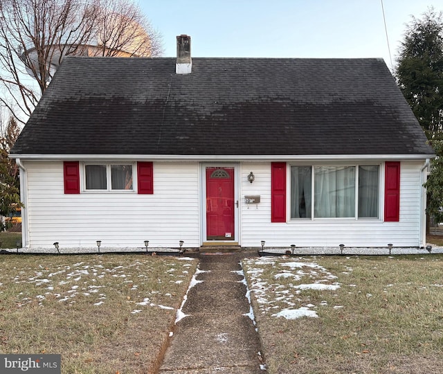 cape cod-style house with a front yard, roof with shingles, and a chimney