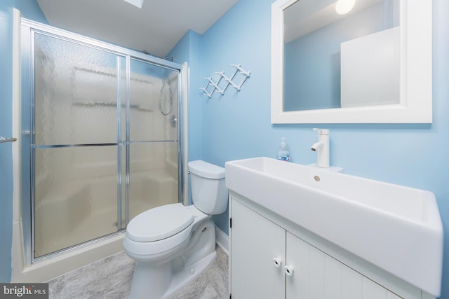 bathroom featuring toilet, a shower with shower door, and vanity