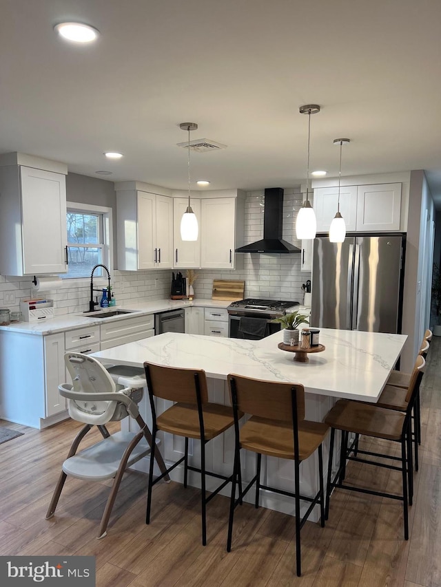 kitchen featuring sink, white cabinets, appliances with stainless steel finishes, and wall chimney exhaust hood