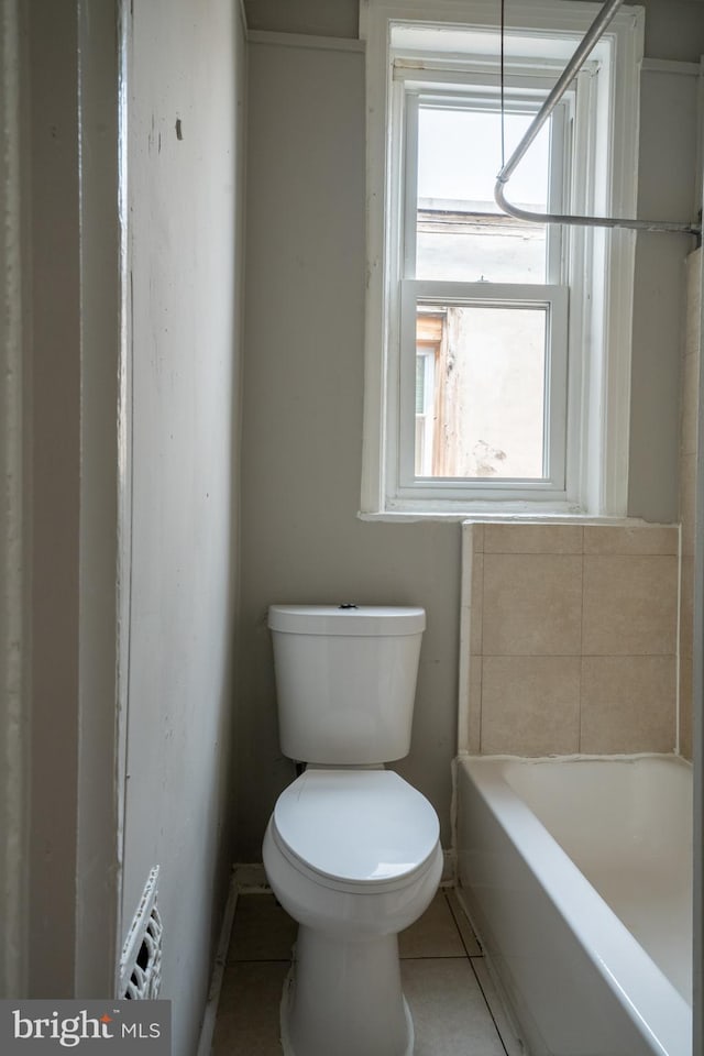 bathroom with toilet, tile patterned flooring, and a washtub