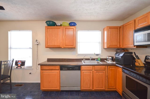 kitchen featuring a textured ceiling, stainless steel appliances, and sink