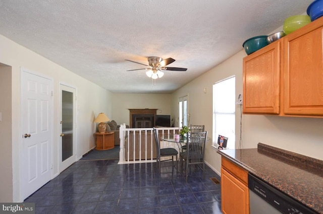 kitchen featuring a textured ceiling, ceiling fan, dark stone countertops, and dishwasher