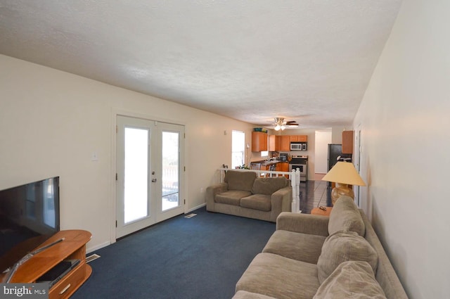 living room featuring a textured ceiling, dark colored carpet, french doors, and ceiling fan