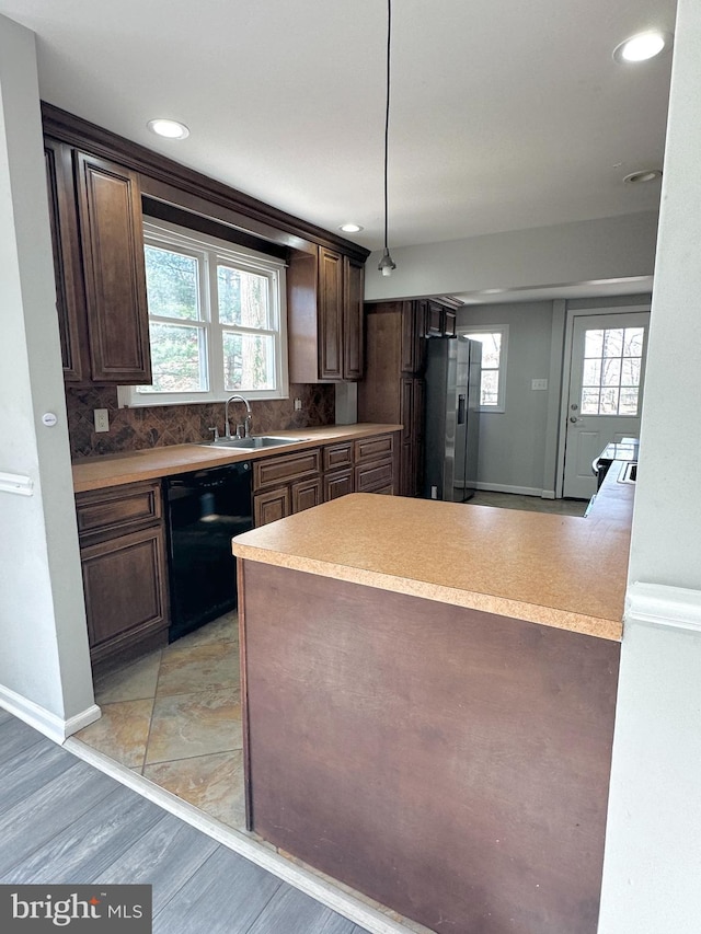 kitchen featuring decorative light fixtures, black dishwasher, backsplash, kitchen peninsula, and stainless steel refrigerator with ice dispenser