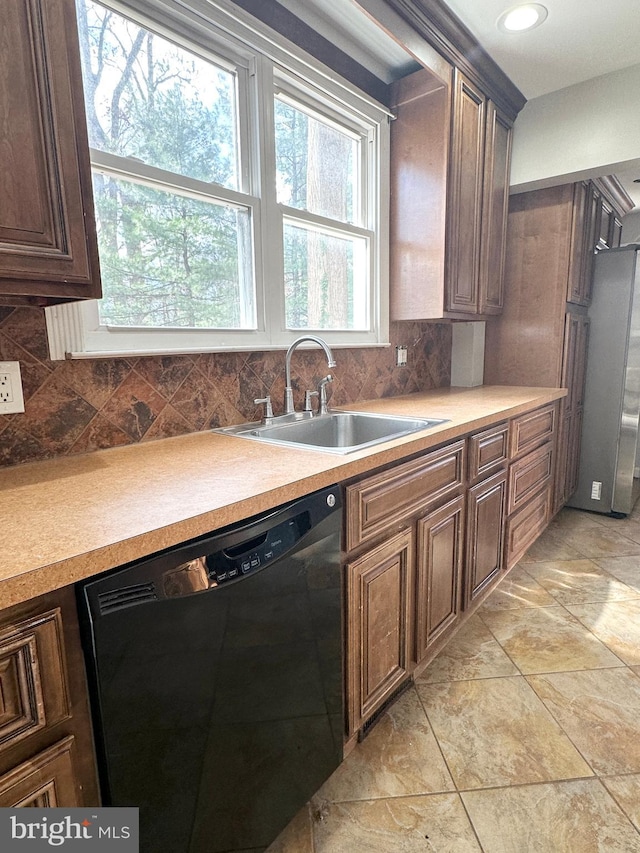 kitchen with sink, light tile patterned floors, stainless steel refrigerator, black dishwasher, and tasteful backsplash