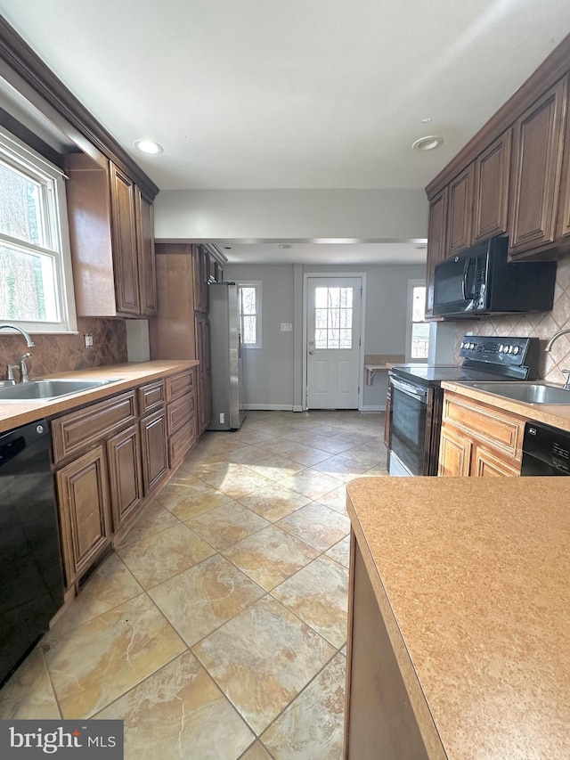 kitchen featuring sink, backsplash, and black appliances