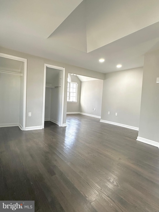 unfurnished bedroom featuring a walk in closet and dark wood-type flooring