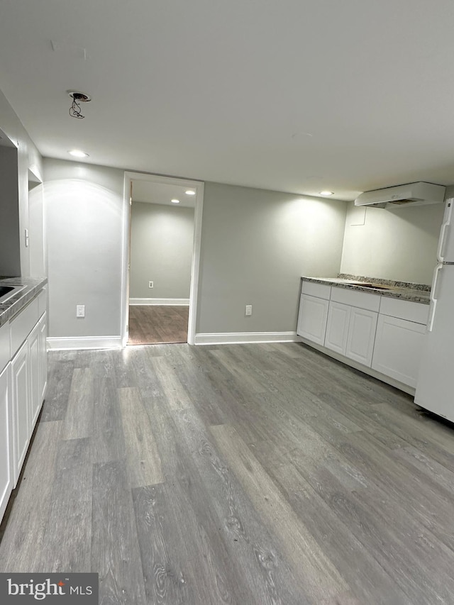 basement featuring light hardwood / wood-style flooring and white fridge