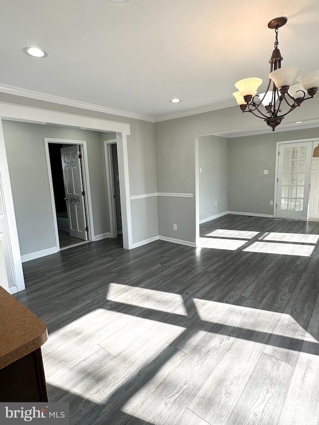 spare room featuring crown molding, dark wood-type flooring, and a notable chandelier