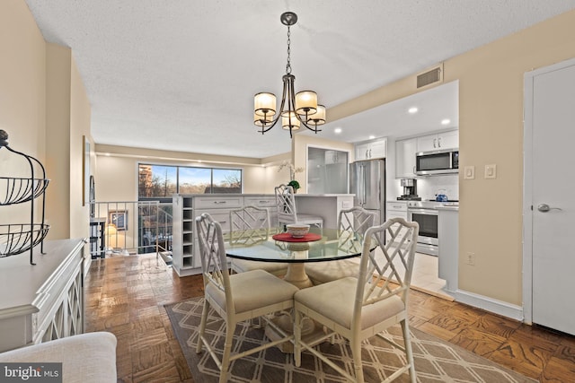 dining room featuring parquet flooring, a textured ceiling, and an inviting chandelier