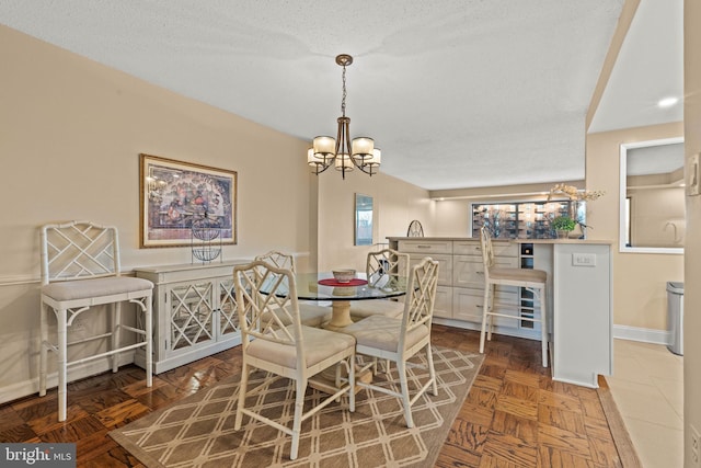 dining area featuring an inviting chandelier, dark parquet floors, and a textured ceiling