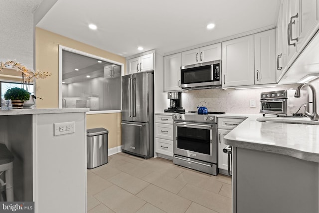 kitchen with sink, white cabinetry, kitchen peninsula, stainless steel appliances, and backsplash