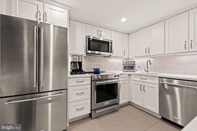 kitchen with appliances with stainless steel finishes, sink, decorative backsplash, and white cabinets