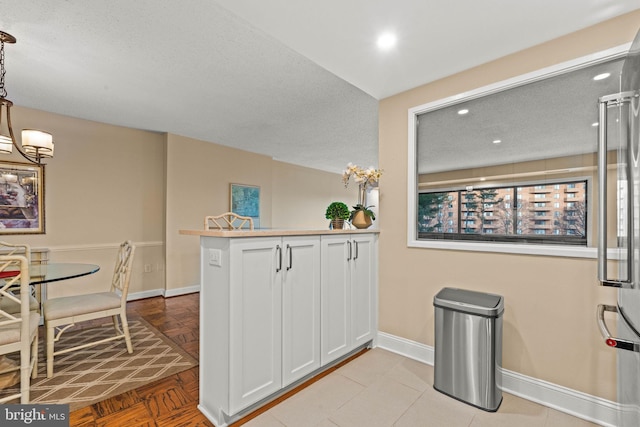 kitchen with pendant lighting, kitchen peninsula, a textured ceiling, and white cabinets