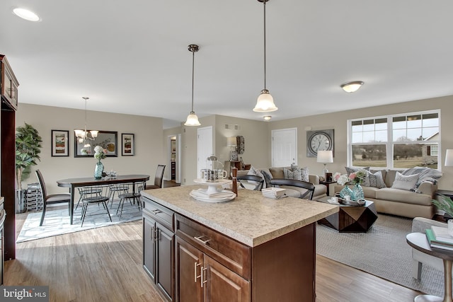 kitchen with pendant lighting, light wood-type flooring, an inviting chandelier, and a kitchen island