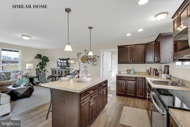 kitchen featuring dark brown cabinetry, a center island, decorative light fixtures, light hardwood / wood-style floors, and a kitchen breakfast bar