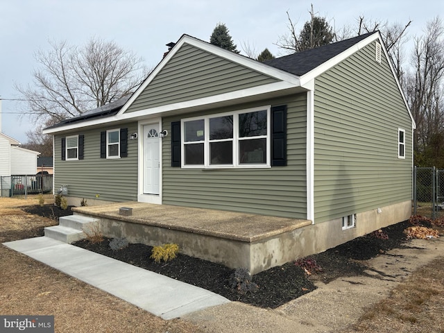 view of front of home featuring roof mounted solar panels and fence