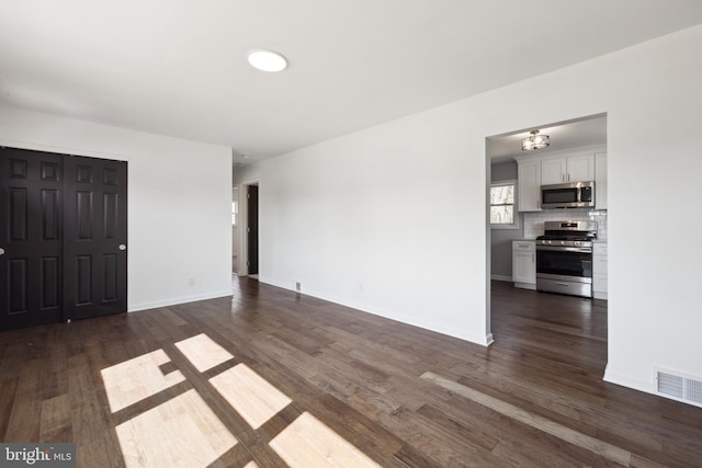 unfurnished living room with visible vents, baseboards, and dark wood finished floors