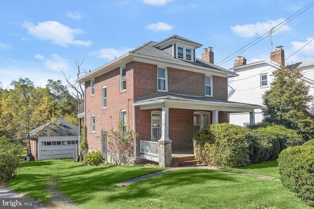 front facade featuring a front lawn, a garage, a porch, and an outbuilding