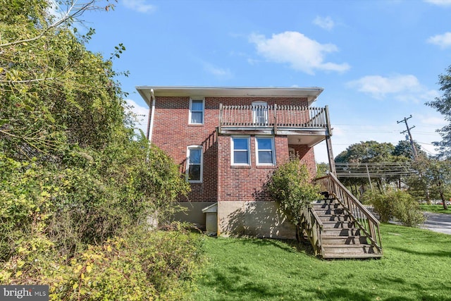 rear view of house with a balcony and a lawn