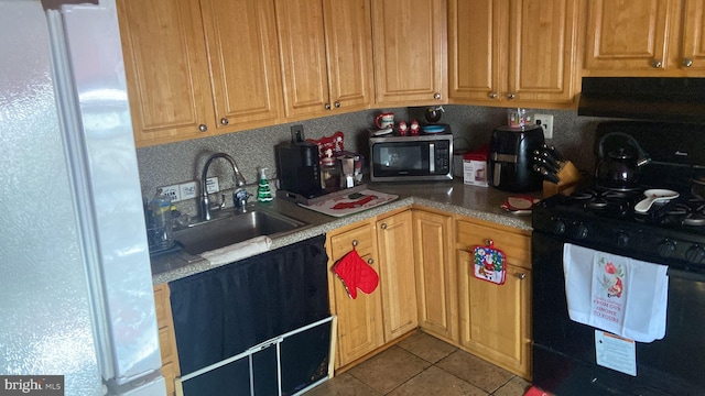 kitchen featuring exhaust hood, white refrigerator, sink, light tile patterned flooring, and black range with gas stovetop