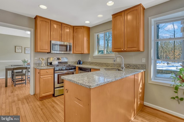 kitchen with light stone countertops, appliances with stainless steel finishes, a wealth of natural light, and sink