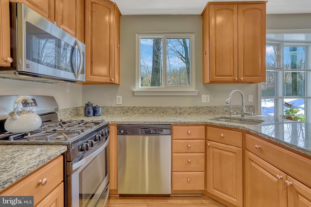 kitchen featuring appliances with stainless steel finishes, light stone counters, and sink