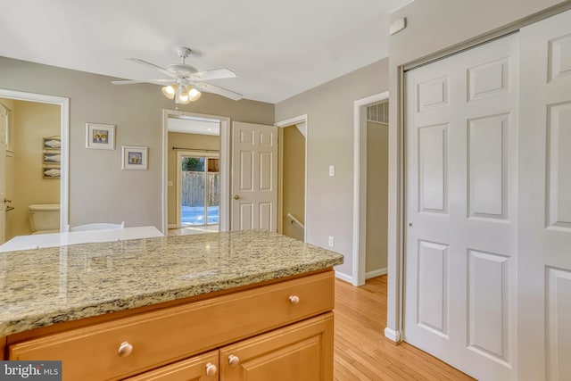 kitchen with ceiling fan, light stone countertops, and light hardwood / wood-style flooring