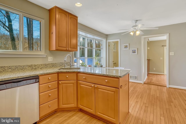 kitchen featuring ceiling fan, light wood-type flooring, light stone countertops, stainless steel dishwasher, and sink