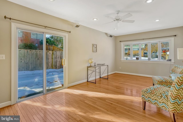 sitting room featuring ceiling fan, wood-type flooring, and a wealth of natural light