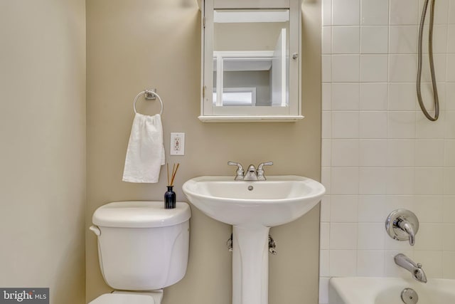 bathroom with toilet and tiled shower / bath