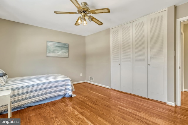 bedroom with ceiling fan, wood-type flooring, and a closet